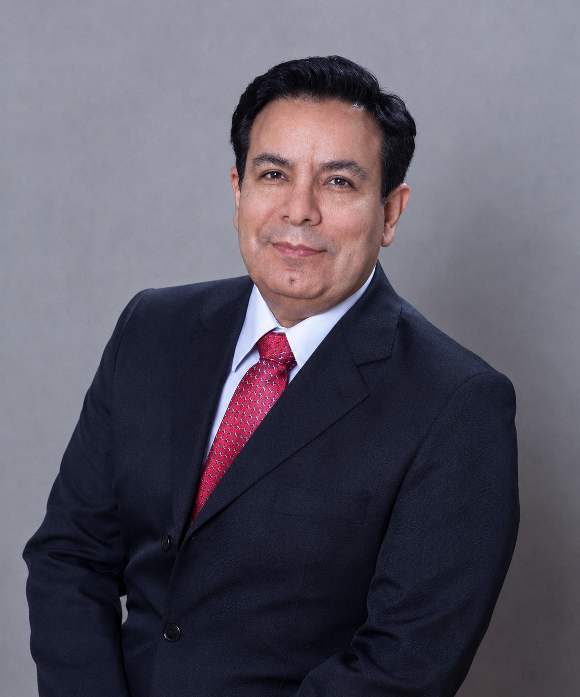 Retrato profesional del Dr. Marco Antonio, médico especialista en trasplante capilar, bata blanca, semblante confiado y acogedor, fondo neutro azul marino, iluminación de estudio suave, fotografía corporativa premium